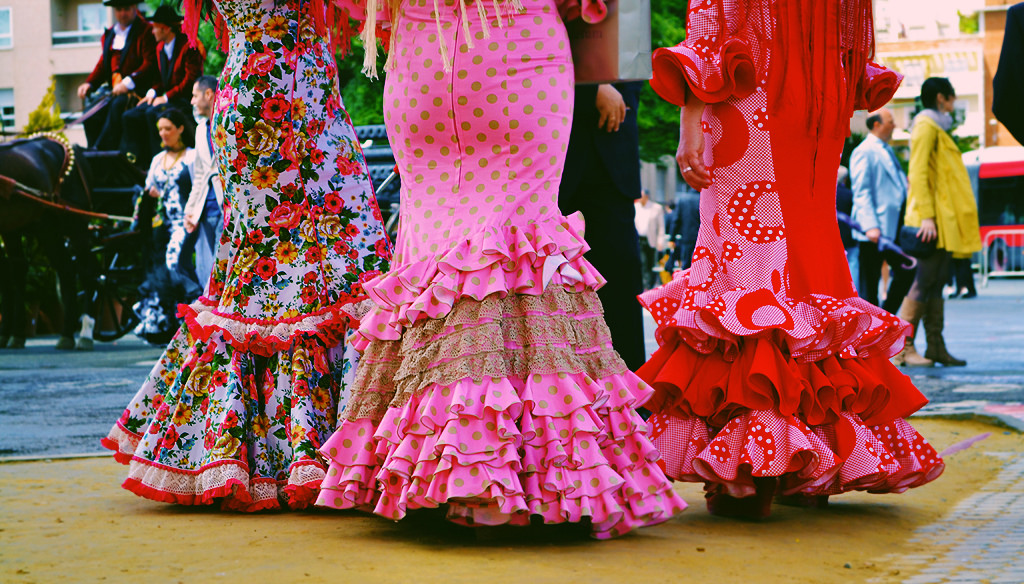 The bottoms half of three women wearing flamenco dresses